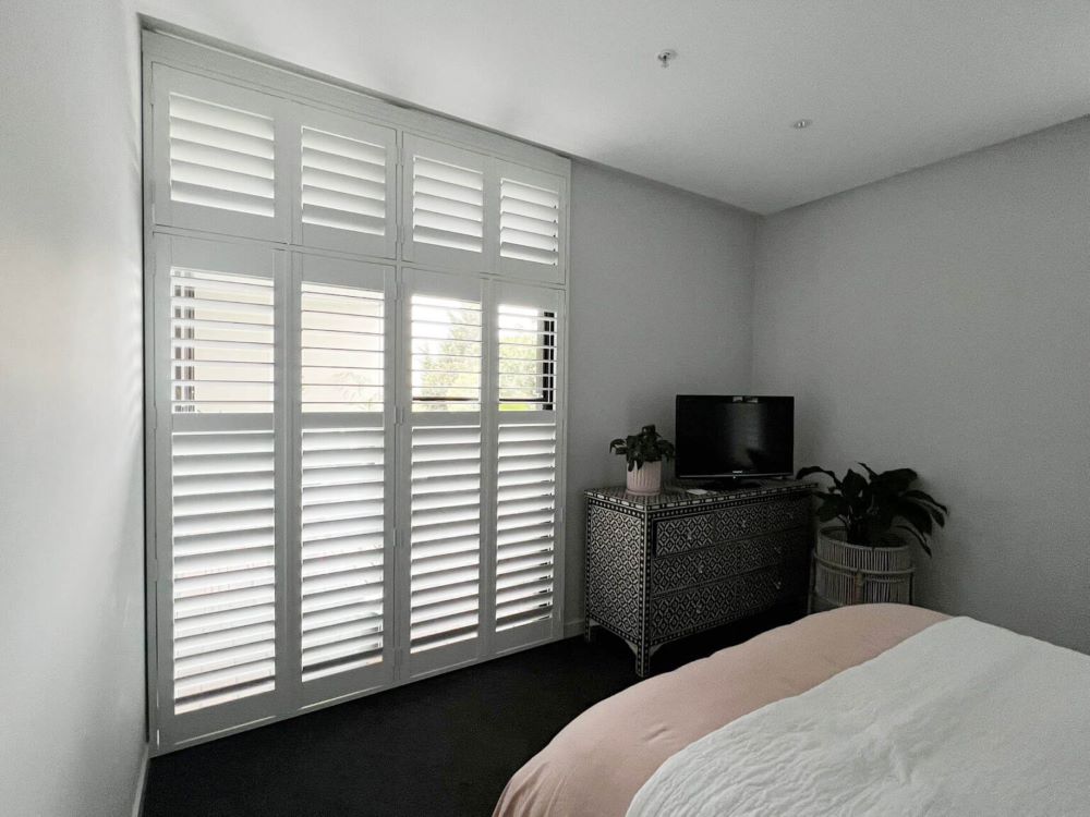 Installing plantation shutters in the bedroom.