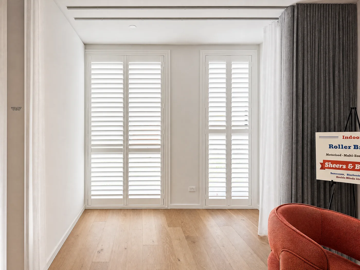 Plantation shutters Melbourne showroom — interior display room with shutters and sheer curtains